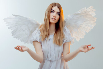 An angel from heaven holding something on the palms. Young, wonderful blonde girl in the image of an angel with white wings.