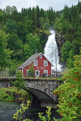 Wasserfall in Norwegen Steinsdalfossen mit Steinbrücke und typischen Norwegenhaus im Vordergrund