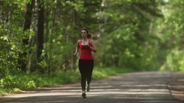 young woman Jogging in summer forest. the girl goes sports in the nature. the model runs towards the camera.