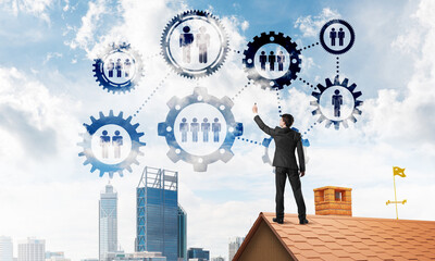Businessman on house roof presenting teamwork and connection concept. Mixed media