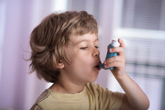 Boy using asthma inhaler to treat inflammatory disease, wheezing, coughing, chest tightness and shortness of breath. Allergy treating concept.