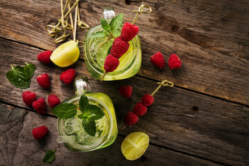 Tasty cold fresh drink lemonades with lemon, mint, raspberry, ice and lime in glass on wooden table. Top View.