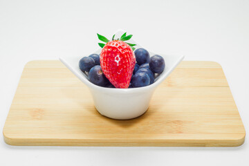 Truskawka i jagody pojemnik biały na desce izolowane białe tło © Sebastian