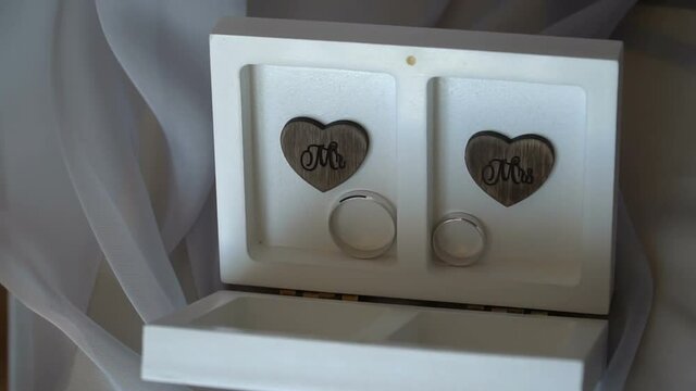 Two wedding rings in a white box with hearts