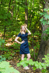 Beautiful woman in elegant dress and charming smile posing in the park. Business girl walks after work