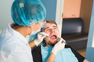 Dental care Concept. Dental inspection is being given to beautiful man surrounded by dentist