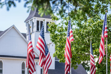 American flags waving outside white church steeple in daylight