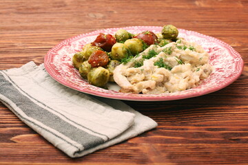 Tasty chicken meat under creamy sauce with brussels sprouts garn