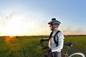 cyclist on Bicycle looks at sunset.