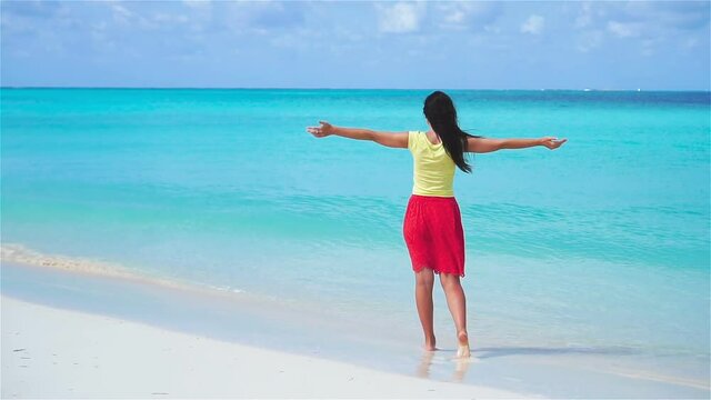 Happy girl at beach walking in shallow water. Slow motion video.