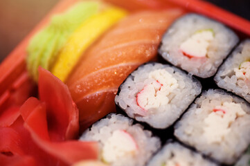 Set salmon rolls in a plastic plate on a black background