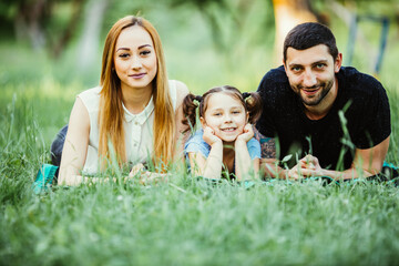 Happy family of three lying on grass. Concept of happy family relations and carefree leisure time