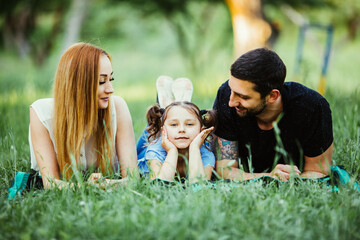 Happy family of three lying on grass. Concept of happy family relations and carefree leisure time