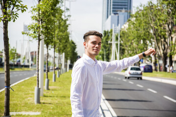 Young handsome man on side of a road, hailing and stopping a taxi cab
