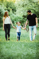 Fototapeta premium happy mother, father and little girl walking in summer park