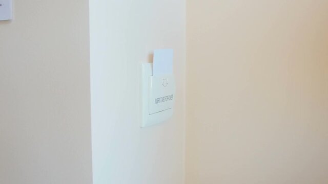 Closeup of woman inserting electronic key card in holder on wall