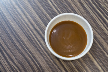 Brown sauce in white cup for seafood and barbecue  on wooden background 