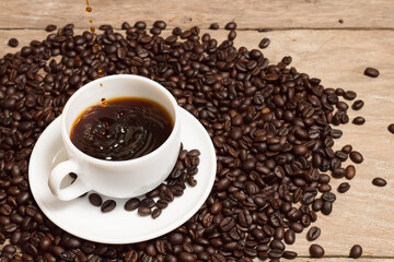 pouring coffee with rosted coffee beans in white cup