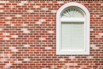 Brick wall with red and grey bricks and a white window.