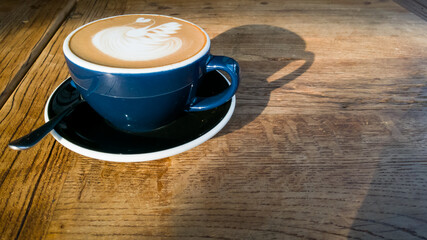Hot mocha coffee or cappuccino in the blue cup with luxury pattern on the wooden table