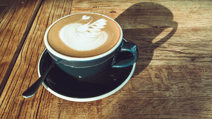 Hot mocha coffee or cappuccino in the blue cup with luxury pattern on the wooden table