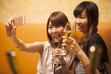 Two women are taking a self picture with alcohol
