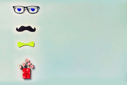 Happy Fathers Day inscription on a blue background. Black mustache, glasses, hipster yellow bow tie, small homemade box with a gift. Concept: Happy Fathers Day. - Powered by Adobe