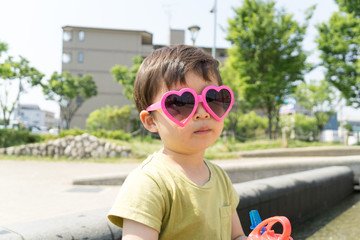 ハートのサングラスをかけた男の子がスイーツを楽しむ夏の屋外ポートレート｜家族レジャー・お祭りイメージに最適な子ども写真