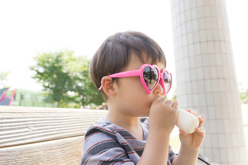 ハートのサングラスをかけた男の子がスイーツを楽しむ夏の屋外ポートレート｜家族レジャー・お祭りイメージに最適な子ども写真