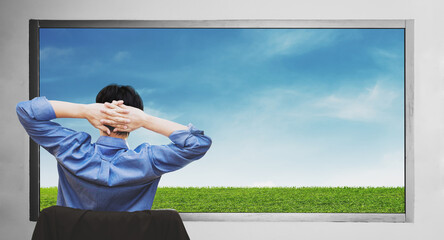 a man stretching arm, looking through window enjoying grass lawn and blue sky view