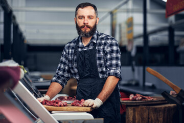 Bearded butcher serving fresh cut meat.