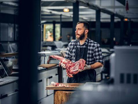Portrait of a bearded meat man holds fresh cut meat.