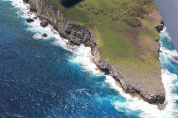 Obraz premium Sharp cliff drops and waves Huge waves slap against sharp rocks below steep cliff drops
