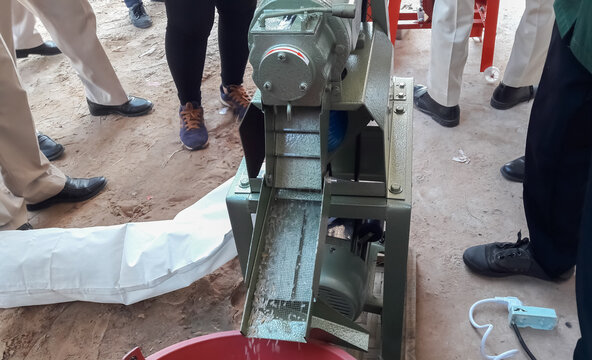 Employees demonstrating the use of small rice mills.