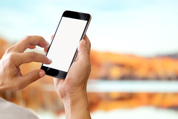 Man holding smart phone with blurred backgroung. Blank screen for Graphic display montage.