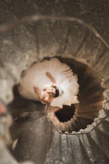 Beautiful bride in magnificent dress stands alone on stairs