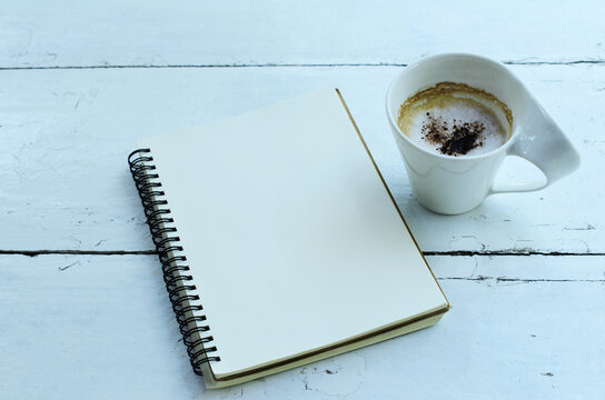Cup of cappuccino and notebooks on wooden table backgrounds