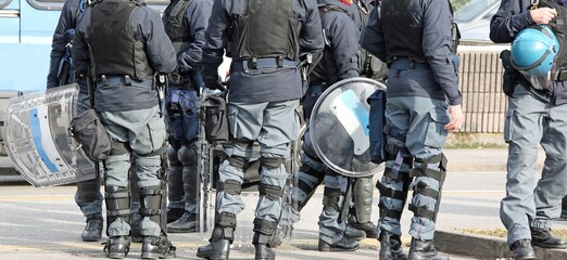 group of riot police with batons and shields during security checks through the streets of the city