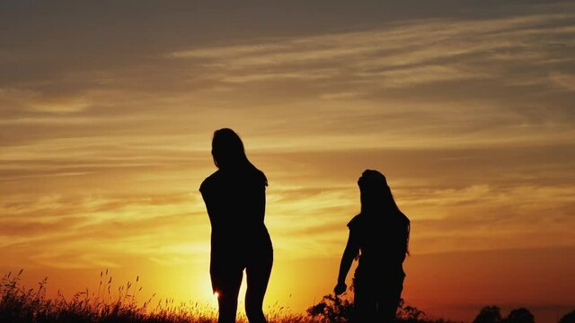 Silhouette of jumping girls at sunset. Slow motion 180 fps
