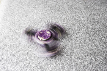Fototapeta na wymiar Fidget spinner purple colour stress relieving toy on grey.