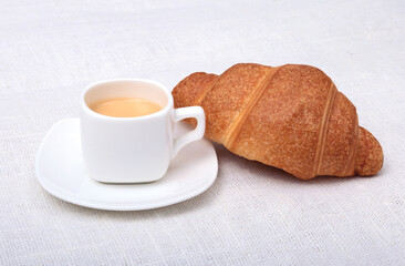 Crispy fresh croissants and cup of coffee espresso on a white background, morning breakfast, selective focus