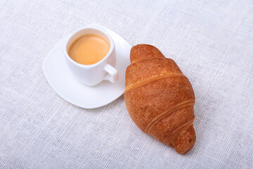 Crispy fresh croissants and cup of coffee espresso on a white background, morning breakfast, selective focus