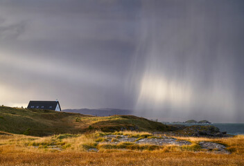 A heavy rain shower over a croft  at Loch Ewe, Scottish Highlands, Scotland, UK.