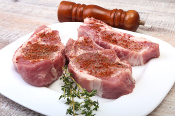 Raw pork chops and spice grinder on cutting board. Ready for cooking.