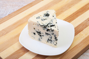 Plate with Tasty blue cheese on wooden table