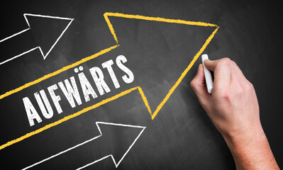 Hand schreibt Pfeile auf Tafel mit Slogan "Aufwärts" 