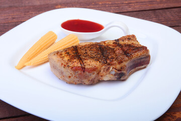 grilled pork chop with Cranberry sauce and Mini Corn cob preserved on plate on wooden board