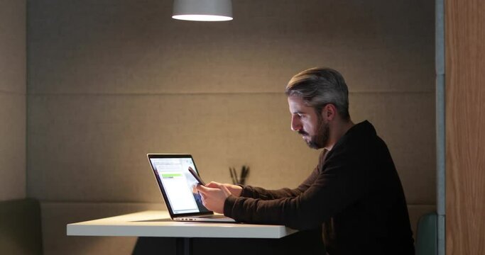 Businessman working late at night in office using smartphone