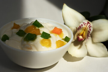Yogurt with slices of fruit, candied fruits and white orchid flower