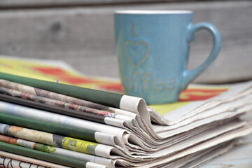 Stacked and piled up newspapers on a wooden table background
